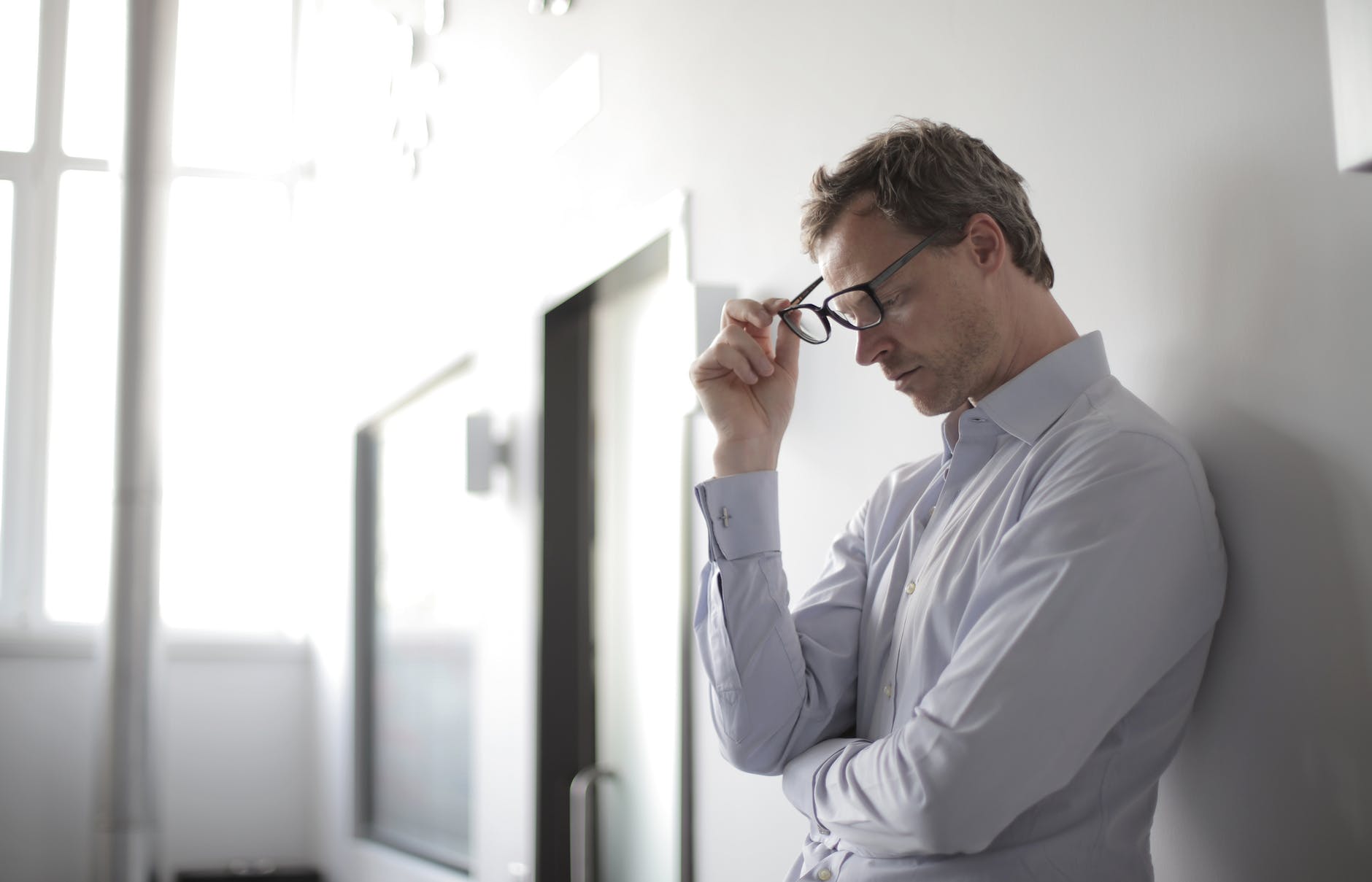photo of man holding black eyeglasses, manage leadership stress